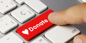 Person pressing a donate button on a keyboard.